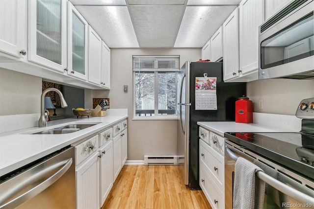 kitchen with baseboard heating, light countertops, white cabinetry, a sink, and stainless steel appliances