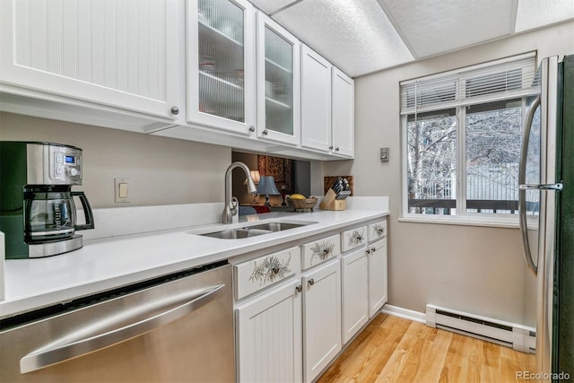 kitchen with stainless steel dishwasher, white cabinets, a baseboard heating unit, and a sink