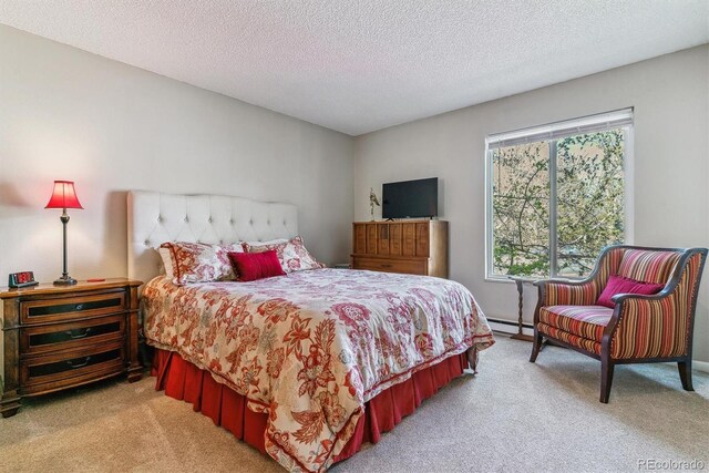 bedroom featuring a baseboard heating unit, a textured ceiling, and light colored carpet