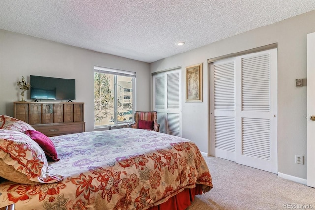carpeted bedroom featuring baseboards, recessed lighting, a textured ceiling, and two closets