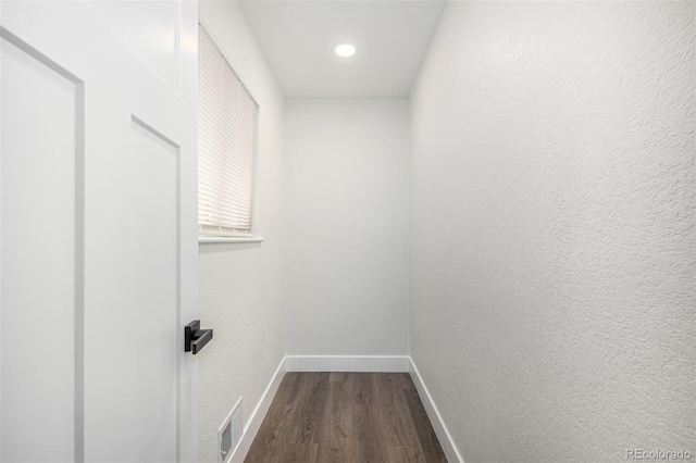 hall with visible vents, baseboards, dark wood-type flooring, and a textured wall