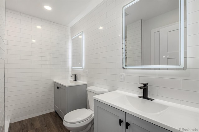 bathroom with a sink, two vanities, tile walls, and wood finished floors