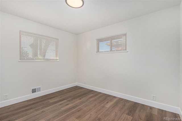 empty room with visible vents, baseboards, and wood finished floors