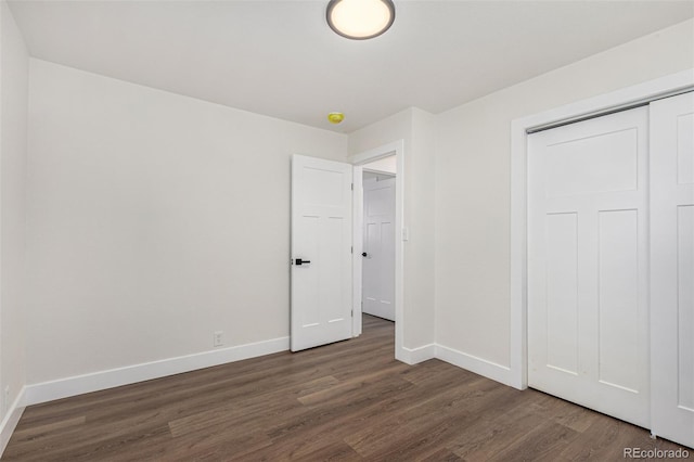 unfurnished bedroom with wood finished floors, baseboards, and a closet