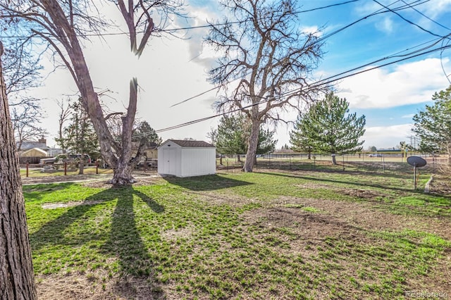 view of yard featuring a storage shed, fence, and an outbuilding