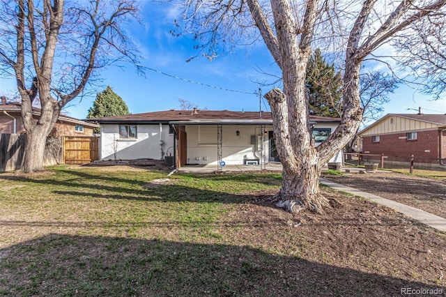 back of house with stucco siding, a lawn, a patio, and fence