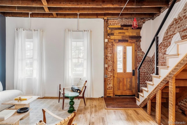 foyer entrance with beam ceiling, brick wall, and hardwood / wood-style flooring