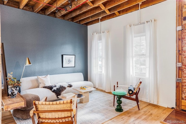 sitting room with beam ceiling and wood-type flooring