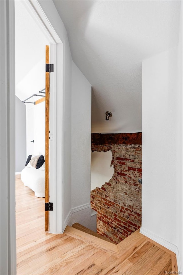 hall featuring wood-type flooring and brick wall