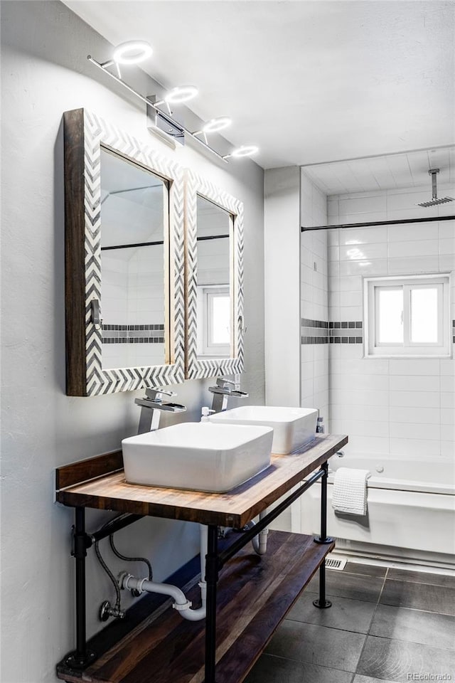 bathroom with tiled shower / bath combo, a healthy amount of sunlight, and sink