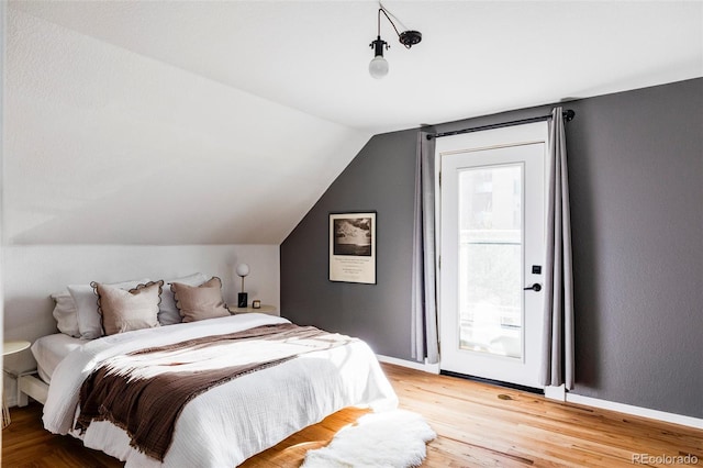 bedroom with wood-type flooring and vaulted ceiling