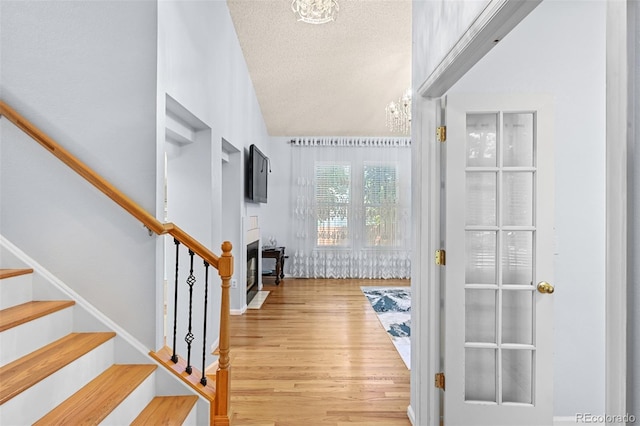 entryway featuring wood finished floors, stairs, a textured ceiling, and vaulted ceiling