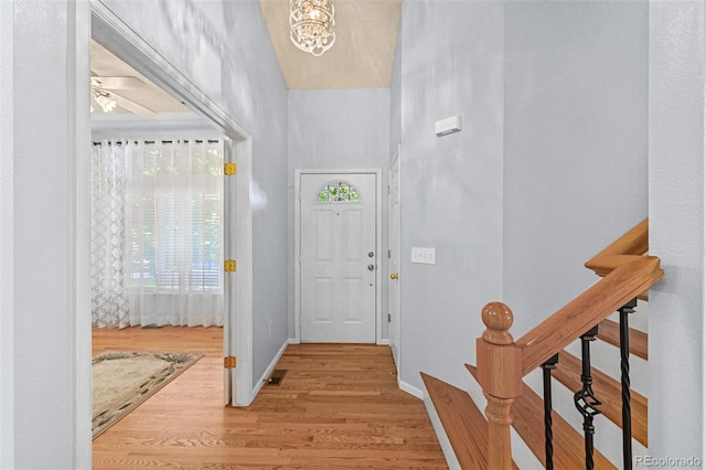 entrance foyer featuring wood finished floors, baseboards, stairway, and a chandelier
