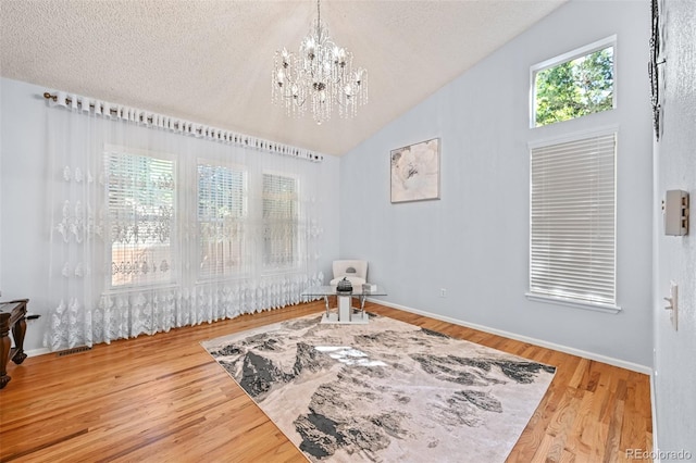sitting room featuring a chandelier, wood finished floors, a textured ceiling, lofted ceiling, and baseboards