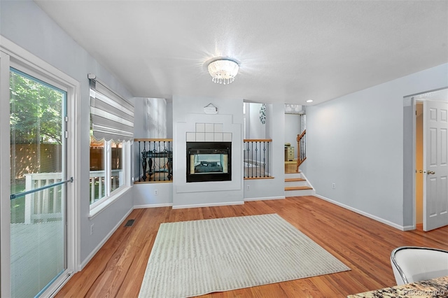 unfurnished living room featuring wood finished floors, stairway, a chandelier, and baseboards
