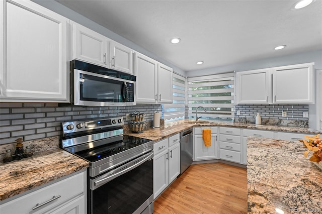 kitchen with stainless steel appliances, a sink, white cabinets, and recessed lighting