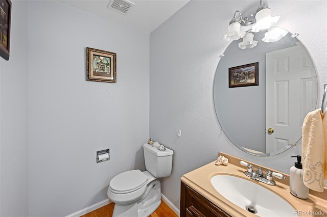 bathroom featuring toilet, a chandelier, vanity, wood finished floors, and baseboards