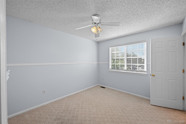 spare room featuring carpet, a textured ceiling, a ceiling fan, and baseboards
