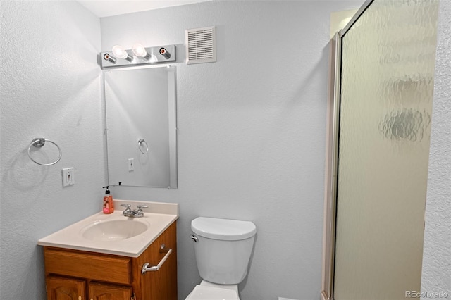 bathroom with a shower stall, toilet, and vanity