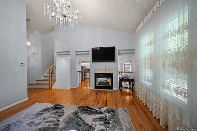 living area featuring a chandelier, wood finished floors, a textured ceiling, stairway, and lofted ceiling