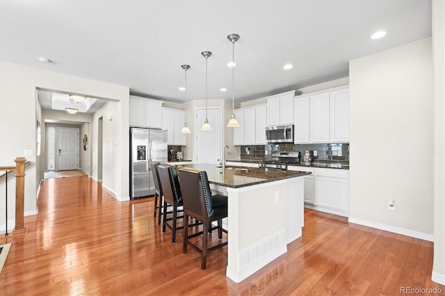 6174 Flattop St, Golden, CO 80403 - kitchen featuring appliances with stainless steel finishes, a sink, a kitchen bar, backsplash, and white cabinetry