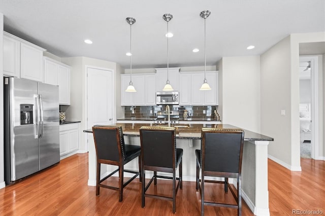 6174 Flattop St, Golden, CO 80403 - kitchen featuring appliances with stainless steel finishes, light wood-style flooring, backsplash, white cabinets, and hanging light fixtures