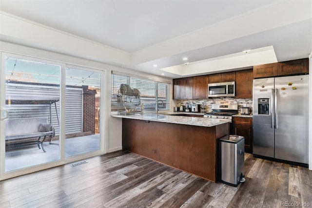 625 S Xenon Ct, Lakewood, CO 80228 - kitchen with stainless steel appliances, dark wood-type flooring, a peninsula, dark brown cabinets, and light stone counters