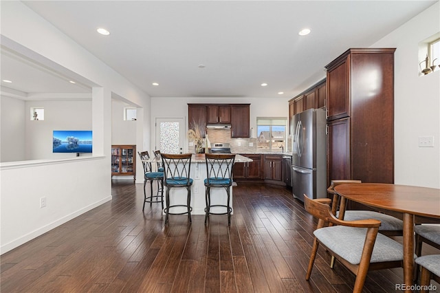 kitchen with a kitchen island, appliances with stainless steel finishes, dark hardwood / wood-style flooring, decorative backsplash, and a healthy amount of sunlight