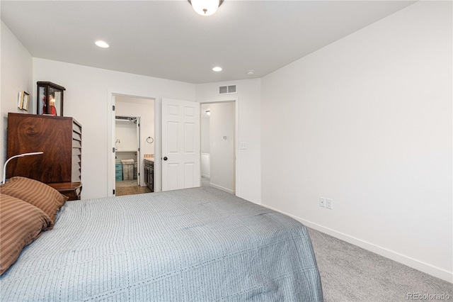 bedroom featuring ensuite bathroom and carpet flooring