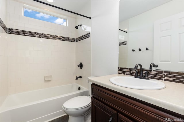 full bathroom featuring tiled shower / bath, vanity, and toilet