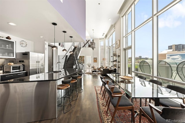 55 W 12th Ave Unit 608, Denver, CO 80204 - kitchen featuring stainless steel fridge, dark wood-style flooring, a kitchen breakfast bar, pendant lighting, and dark countertops