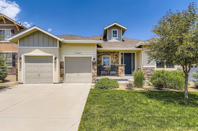 21855 E Idyllwilde Dr, Parker, CO 80138 - view of front of house featuring an attached garage, stone siding, concrete driveway, a front yard, and covered porch
