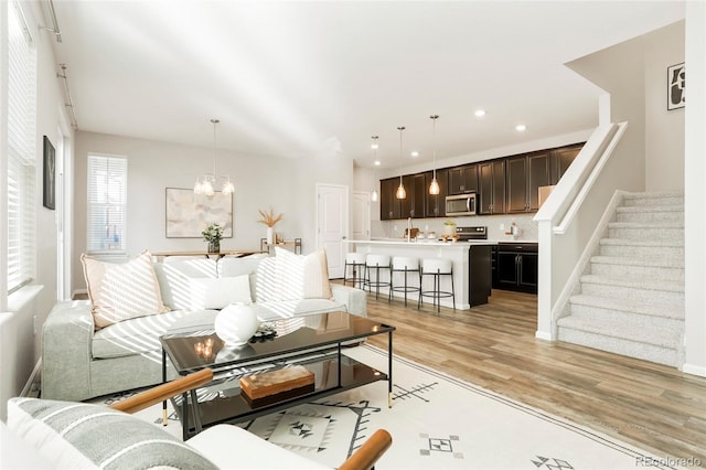 6041 N Orleans St, Aurora, CO 80019 - living room with a chandelier, light wood-style floors, stairway, recessed lighting, and baseboards
