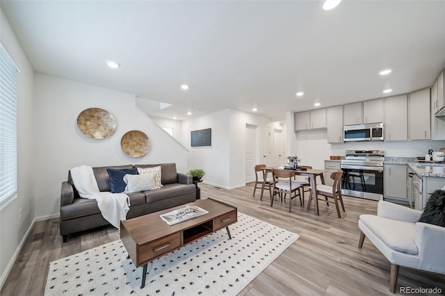 living area with recessed lighting, light wood-type flooring, and baseboards