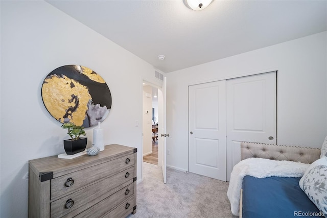 bedroom with visible vents, light colored carpet, and a closet