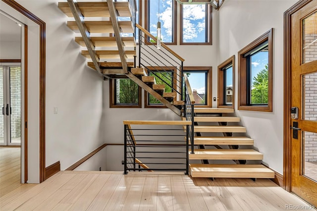 staircase featuring a towering ceiling and wood-type flooring