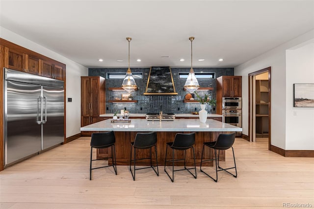 kitchen featuring appliances with stainless steel finishes, a kitchen island with sink, sink, pendant lighting, and backsplash