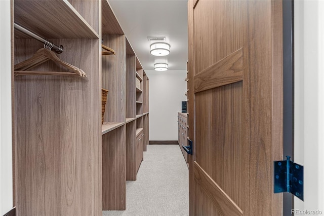 spacious closet featuring light colored carpet