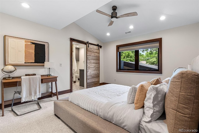 bedroom featuring ceiling fan, ensuite bathroom, a barn door, and vaulted ceiling