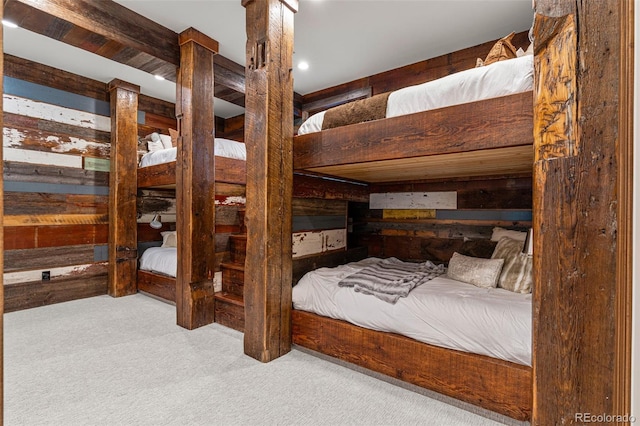 carpeted bedroom with beam ceiling and wooden walls