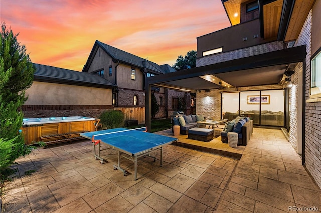 patio terrace at dusk featuring an outdoor living space and a hot tub