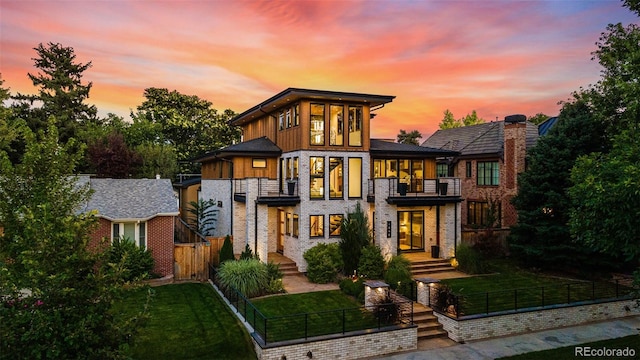 view of front of property featuring a balcony and a yard