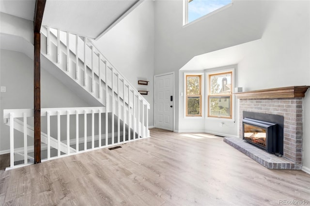 1740 S Ammons St Unit C, Lakewood, CO 80232 - unfurnished living room featuring healthy amount of natural light, wood finished floors, baseboards, a towering ceiling, and a fireplace
