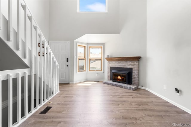 1740 S Ammons St Unit C, Lakewood, CO 80232 - unfurnished living room with a towering ceiling, a brick fireplace, baseboards, and wood finished floors
