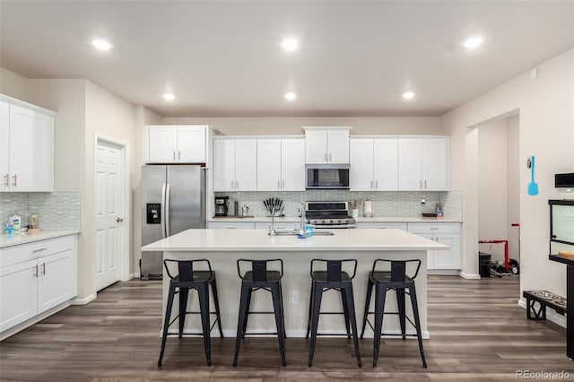 kitchen featuring a center island with sink, white cabinetry, dark wood-type flooring, and stainless steel appliances