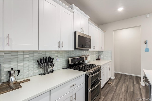 kitchen with white cabinets, backsplash, stainless steel appliances, and dark hardwood / wood-style floors