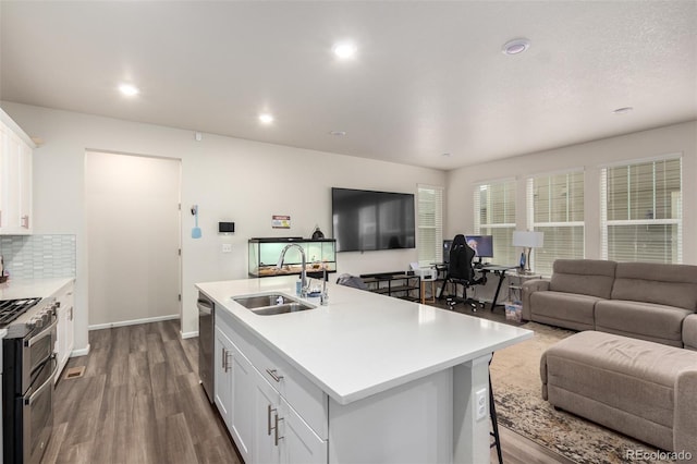 kitchen featuring wood-type flooring, a kitchen island with sink, sink, white cabinetry, and stainless steel appliances