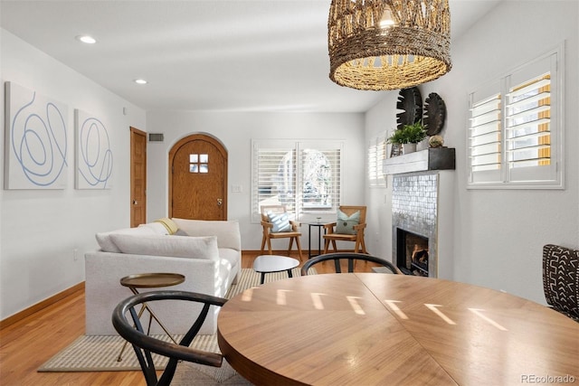 dining room featuring hardwood / wood-style flooring and a tiled fireplace