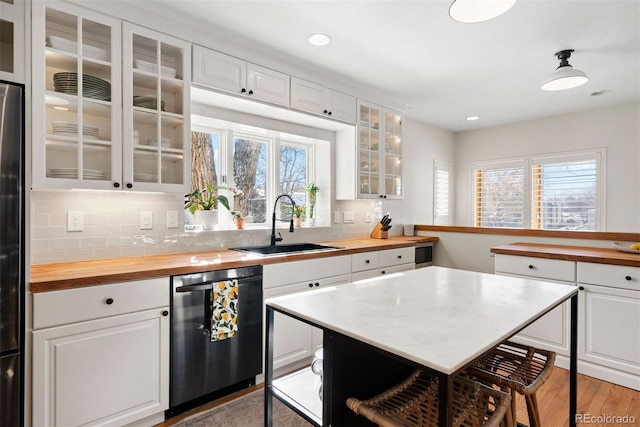 kitchen with light hardwood / wood-style flooring, white cabinets, butcher block countertops, black appliances, and decorative backsplash