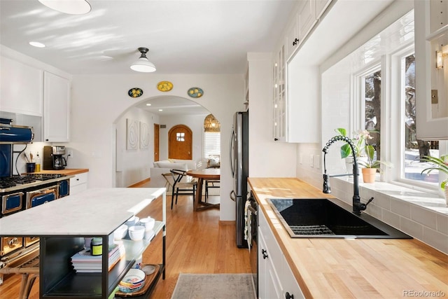 kitchen featuring plenty of natural light, white cabinetry, sink, and butcher block counters